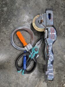 Apple tree tagging materials including Dymo-Mite Tapewriter, metal wire, wire cutters, and awl.