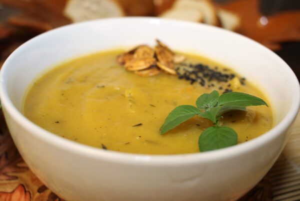 Pumpkin soup in a ceramic bowl, garnished with fresh basil leaves